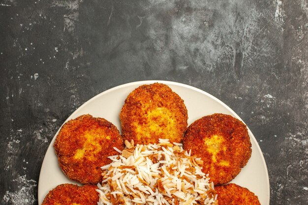 Vista superior saborosas costeletas fritas com arroz cozido na superfície escura foto refeição prato de carne