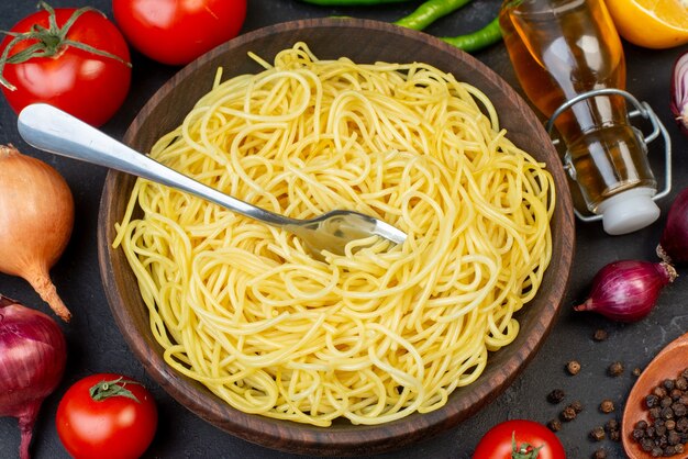 Vista superior saboroso espaguete em tigela tomate azeite cebola na mesa