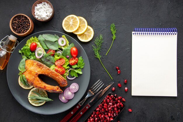 Vista superior saboroso peixe cozido com legumes frescos na mesa escura