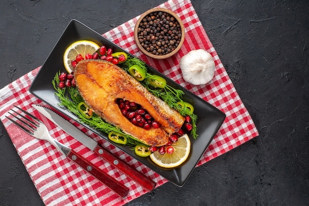 Vista superior saboroso peixe cozido com limão e verduras na mesa escura