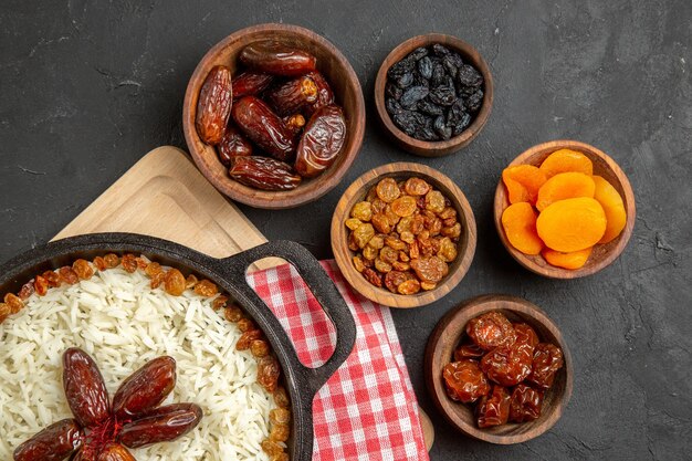 Vista superior saboroso prato de arroz cozido plov com passas diferentes no fundo escuro prato de passas comida arroz óleo jantar