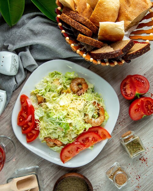 Vista superior salada Caesar com fatias de tomate camarão e um copo de refrigerante