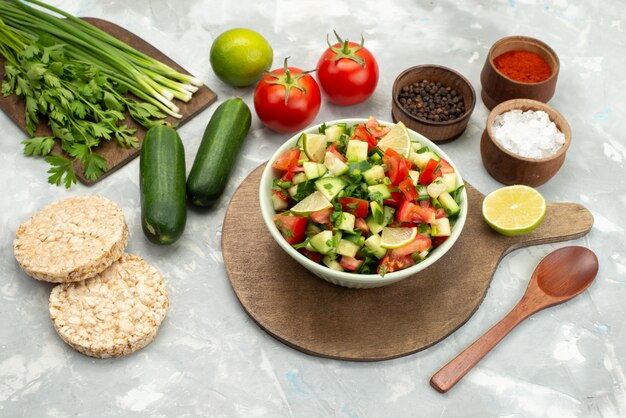 Vista superior salada de legumes frescos com legumes fatiados e rodelas de limão dentro de prato redondo com verdes no azul