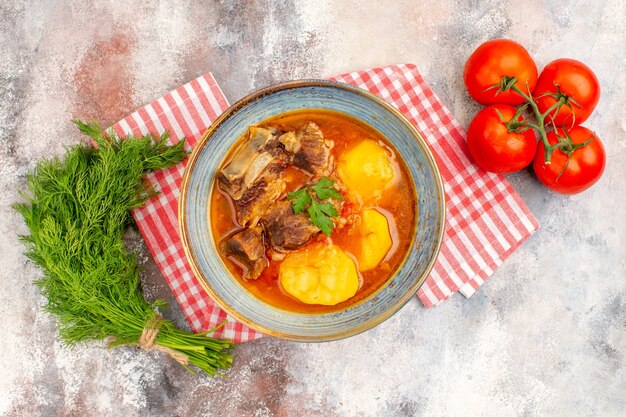 Vista superior, sopa bozbash caseira, toalha de cozinha, um monte de tomates de endro em um fundo nu