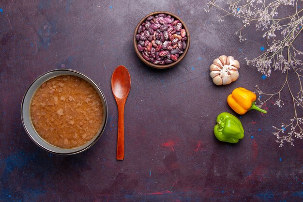 Vista superior sopa marrom dentro do prato com feijão na superfície escura sopa refeição de vegetais alimentos óleo de cozinha