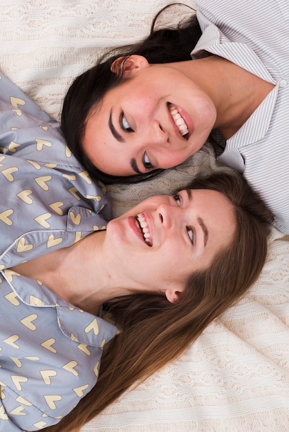 Vista superior sorridente jovens melhores amigos, deitado na cama