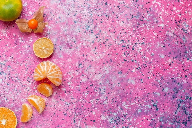 Vista superior tangerinas azedas frescas com limões na mesa rosa claro.