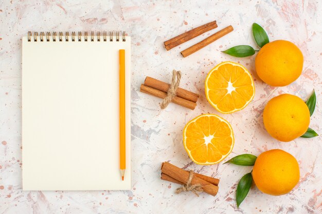 Foto grátis vista superior tangerinas frescas canela em pau um caderno em superfície brilhante