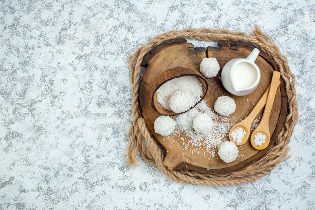 Vista superior tigela de leite tigela de pó de coco colheres de madeira bolas de coco na placa de madeira no fundo cinza