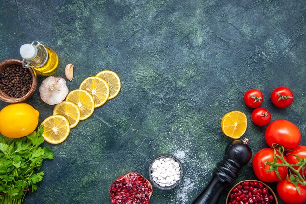 Vista superior, tomate fresco, garrafa de óleo, moedor de pimenta, rodelas de limão na mesa da cozinha com local de cópia