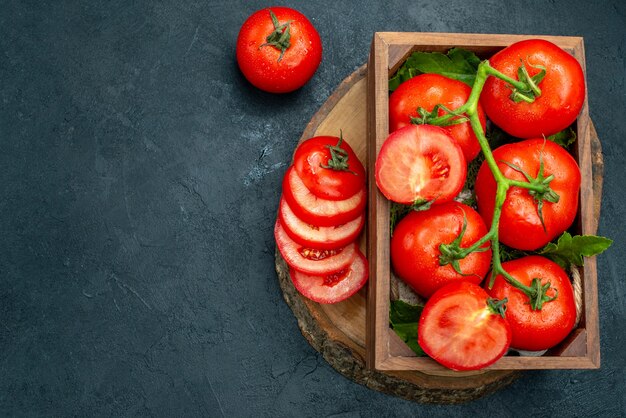 Vista superior tomate vermelho tomate picado em caixa de madeira na placa de madeira na mesa preta
