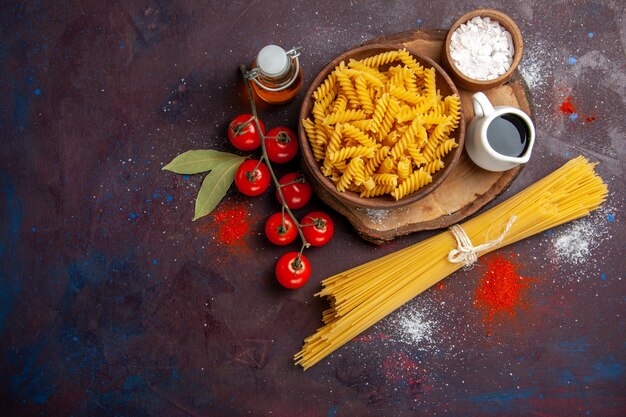 Vista superior, tomates vermelhos frescos com massa italiana crua em fundo escuro comida salada crua refeição de massa