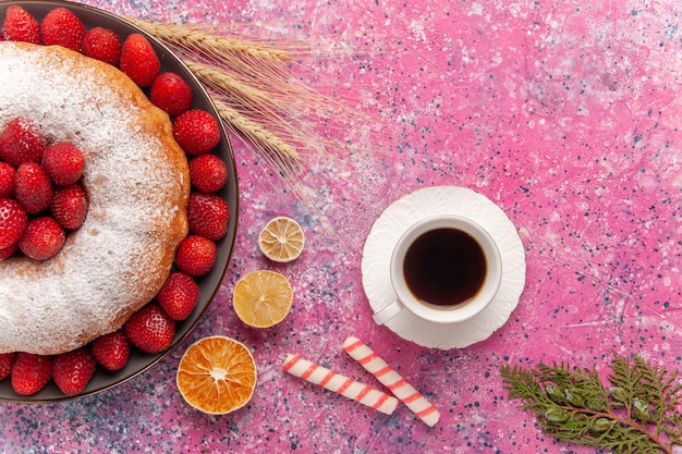 Vista superior torta de açúcar em pó e bolo de morango com uma xícara de chá rosa