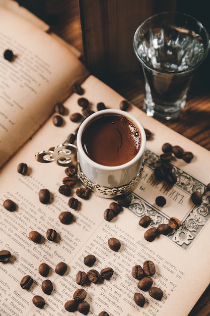 Vista superior tradicional café turco com grãos de café em um livro aberto com um copo de água