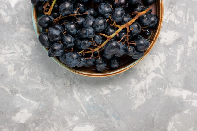 Vista superior uvas pretas frescas suculentas frutas suaves e doces na mesa branca clara