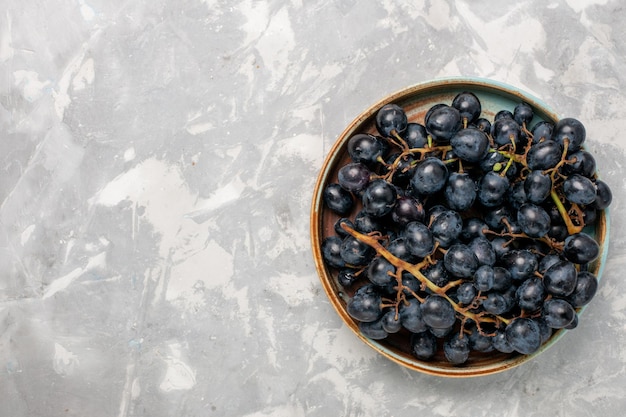 Vista superior uvas pretas frescas suculentas frutas suaves e doces na mesa branca clara