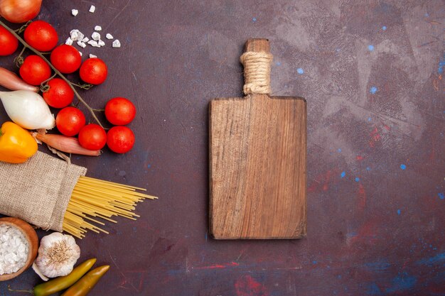 Vista superior vegetais frescos tomates cebolas macarrão e batatas na mesa escura