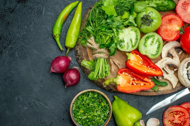 Vista superior vegetais tomates pimentões pepino verdes cogumelos em uma placa de madeira