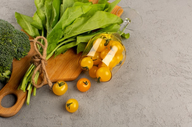 vista superior verde folhas juntamente com brócolis e tomate amarelo sobre o fundo cinza