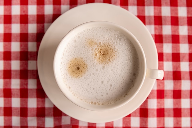 Foto grátis vista superior xícara de café com fundo xadrez