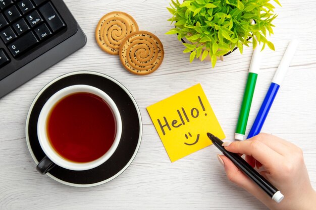 Vista superior xícara de chá com notas de motivação escritas em fundo branco teclado de negócios doce feminino escritório trabalhador