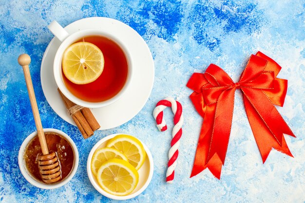 Vista superior xícara de chá laço vermelho natal doce fatias de limão mel na mesa azul