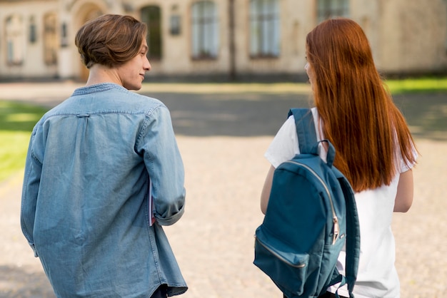 Vista traseira adolescentes caminhando juntos no campus