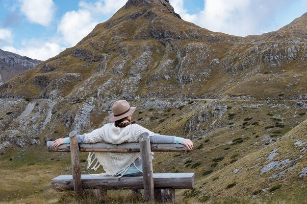 Vista traseira da jovem com chapéu e poncho quente na paisagem montanhosa Durmitor Montenegro