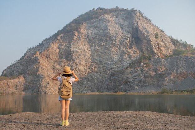 Vista traseira da menina asiática admirando a bela vista das montanhas rochosas e do lago