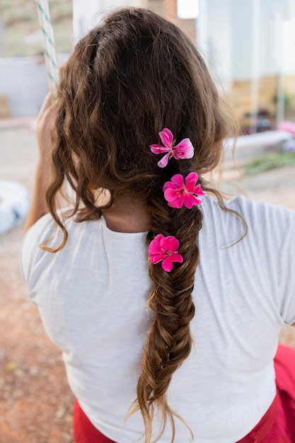 Foto grátis vista traseira da mulher ao ar livre em balanço com flores no cabelo