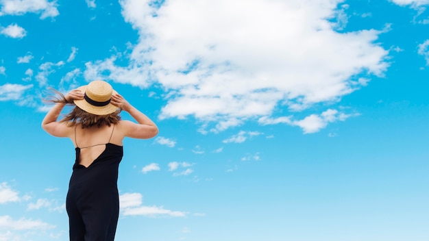 Vista traseira da mulher com chapéu e céu com nuvens