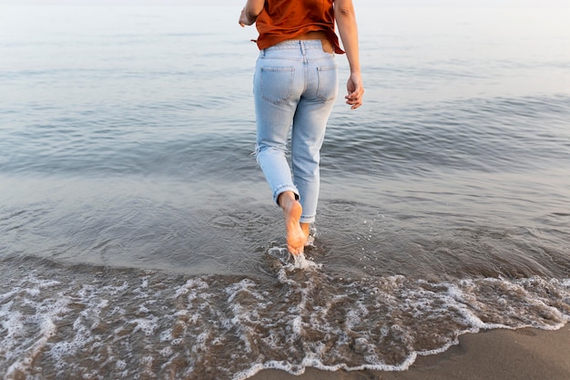 Foto grátis vista traseira da mulher entrando na água na praia