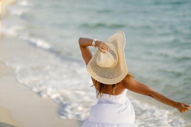 Vista traseira da mulher se sentindo livre enquanto passava o dia de verão na praia
