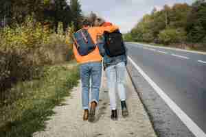 Foto grátis vista traseira de casal caminhando juntos na beira da estrada