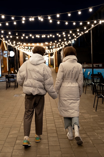 Vista traseira de casal de mãos dadas ao ar livre em luzes