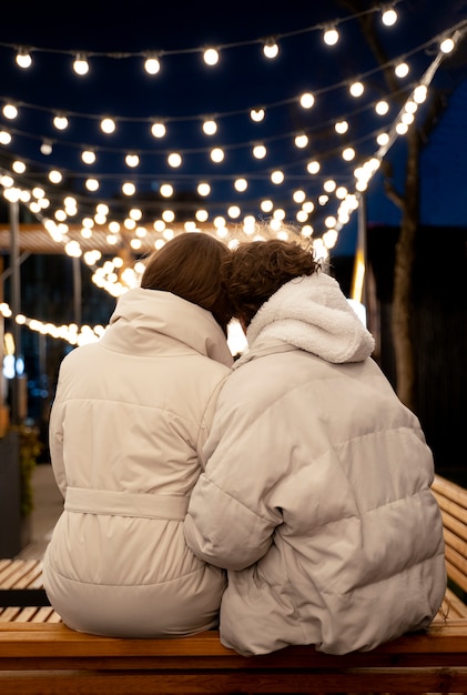 Vista traseira de casal em pé ao ar livre com luzes
