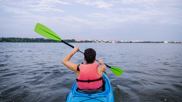 Vista traseira, de, macho, kayaker, remar, caiaque