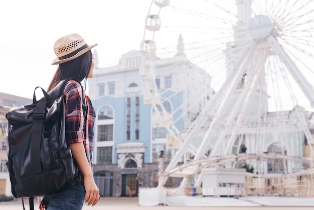 Vista traseira, de, mulher, carregar, mochila, e, olhar, roda ferris