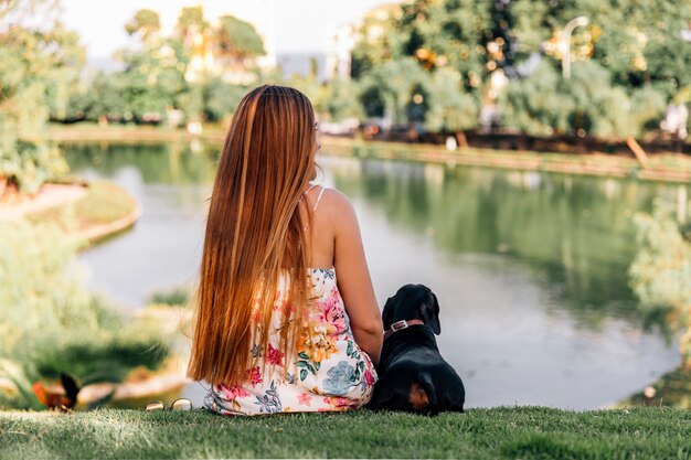 Vista traseira, de, mulher, e, bassê, sentando, perto, a, lagoa