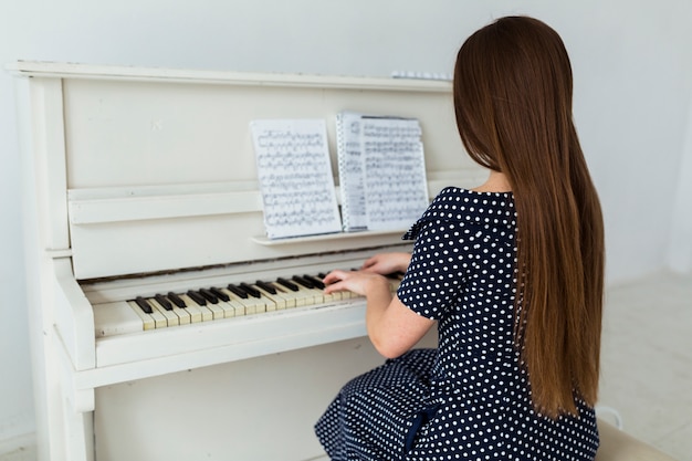 Vista traseira, de, mulher jovem, com, cabelo longo, piano jogo