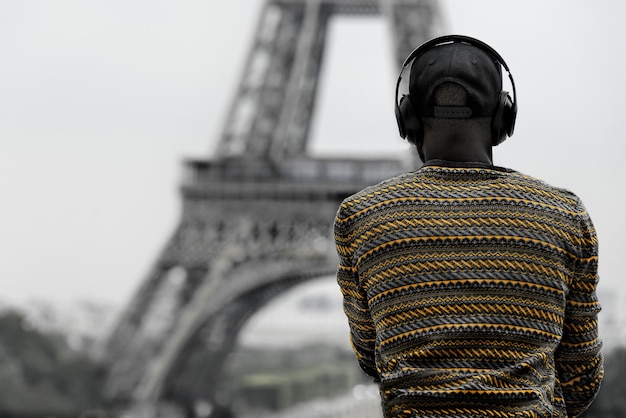 Vista traseira de um homem afro-americano com fones de ouvido e a torre eiffel