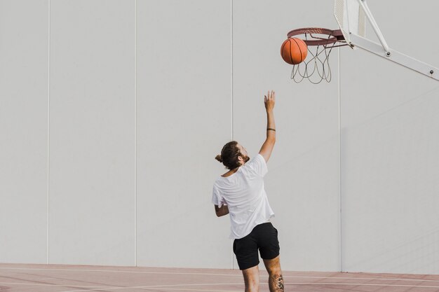 Vista traseira, de, um, homem jovem, jogando basquetebol, em, aro