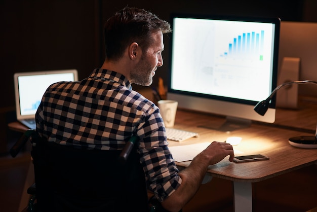 Vista traseira de um homem trabalhando com tecnologia à noite