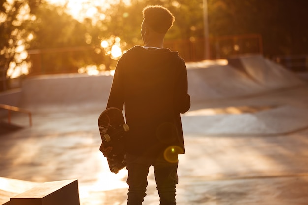 Vista traseira de um jovem adolescente masculino africano com fones de ouvido