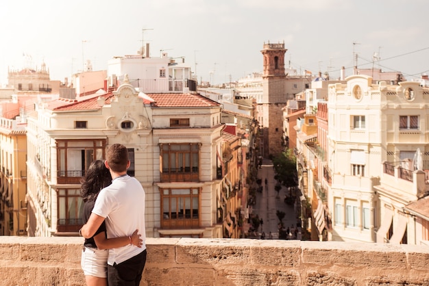 Vista traseira de um jovem casal de turistas olhando edifícios em uma cidade