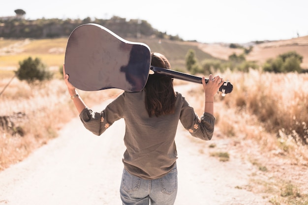 Vista traseira, de, um, menina adolescente, com, guitarra, ficar, ligado, estrada sujeira