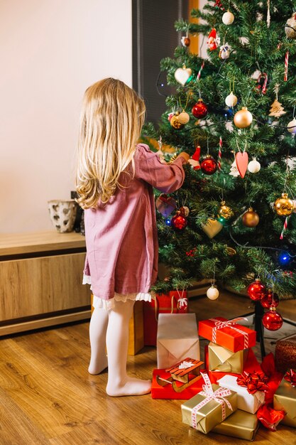 Vista traseira de uma árvore de Natal de decoração de menina