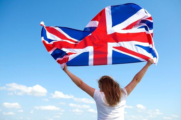 Vista traseira de uma jovem agitando a bandeira britânica