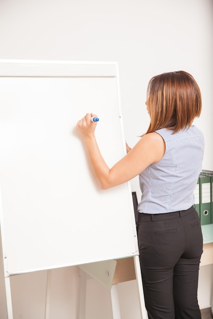 Foto grátis vista traseira de uma jovem professora escrevendo em um flip chart e dando uma aula