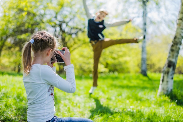 Vista traseira de uma menina tirando uma foto de seu irmão alegre